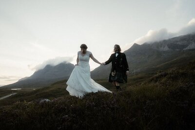 Couple wander across the mountains after their elopement during sunset near Shieldaig, Scotland