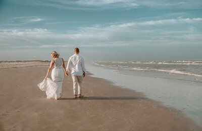 Bride and groom walking along the beach after their intimate wedding in Corpus Christi, Texas.