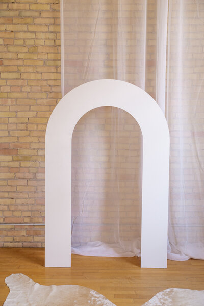 A white wooden arch backdrop with the center cutout to look like a rainbow.