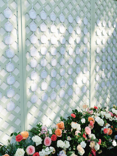 Pastel green seating chart on lattice with florals and dappled light