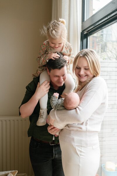 Gezin staat met newborn in armen te kijken naar de baby