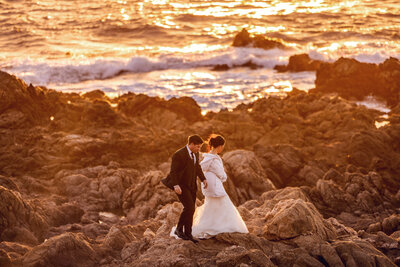 Shannon Lee, an adventure wedding photographer, captures the couple in a beach kissing with a lamp beside them.