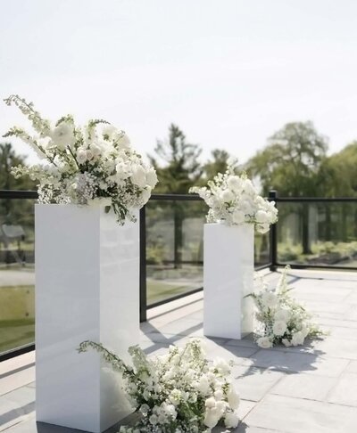 White florals on top of white acrylic wedding plinths
