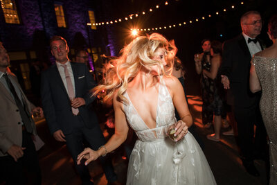 A bride dancing with her guests at her wedding reception.