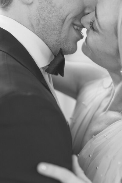 a black and white image of a bride and groom on their wedding day, kissing in the ballroom of elkins estate mansion near philadalphia. image by philadelphia wedding photographer emily wilkerson