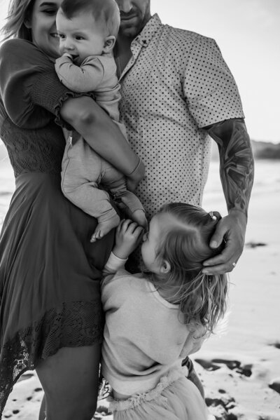 Black and white photo of family cuddling near the beach