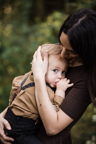 A woman affectionately holding a young child, tenderly placing her hand on the child's head during a family photography session in Pittsburgh, PA.