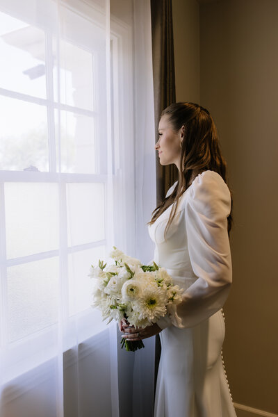 Payton, the bride, taking a moment looking out the window before she walks down the aisle.