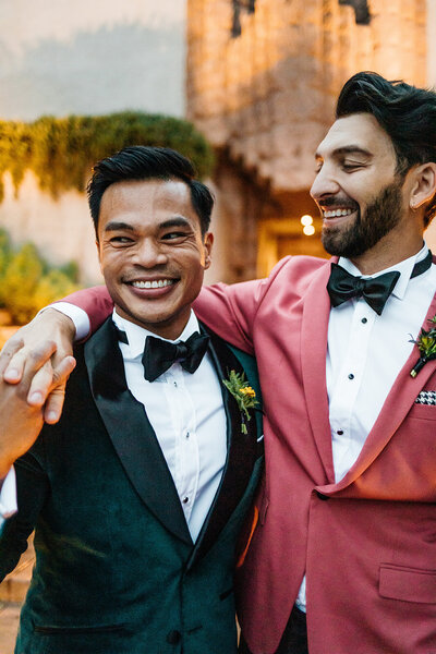 grooms laughing together during sunset photos