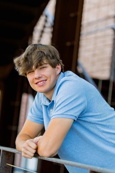senior boy leaning on railing smiling at camera 