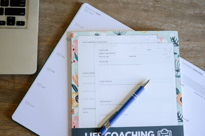 Open coaching journal with a pen, illustrating goal-setting in transformational coaching.