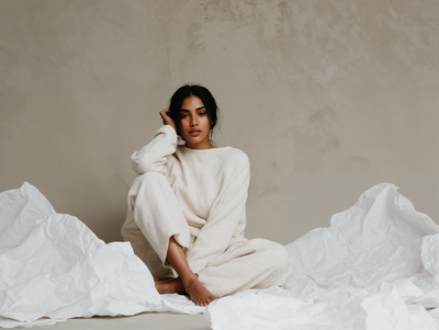 Gina Gold seated in a cozy white setting, reflecting a transformational moment from Jasmina Kimova’s Mirror Method experience