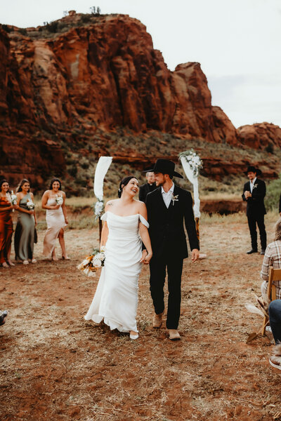 couple smiling while walking up the aisle from their ranch wedding ceremony