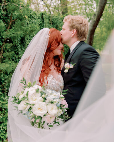Newlyweds kiss outdoors.
