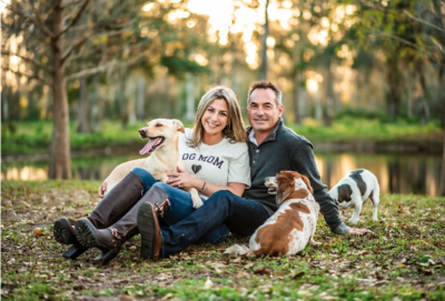 The owners of Cypress Creek Farmhouse, one of the main barn wedding venues Orlando, pose with their dogs on property.