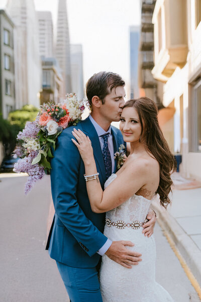 Bride and Groom embrace with lake in background
