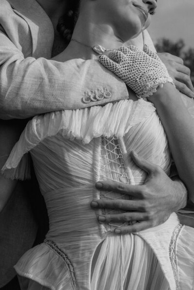 Closeup of a bride in her wedding dress with her groom holding her closely.