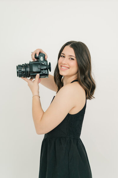 Ephe, a wedding photographer, smiles as she holds her film camera. 
