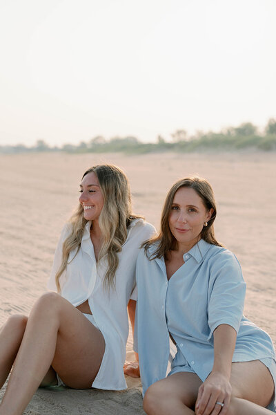 The couple shares a tender embrace at Grand Haven Beach during golden hour, bathed in the warm, soft light of sunset, creating a romantic and intimate moment against the picturesque beach backdrop.