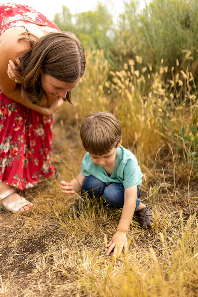 Image of Jenaveve, matrescence coach, and her child looking at something in the grass