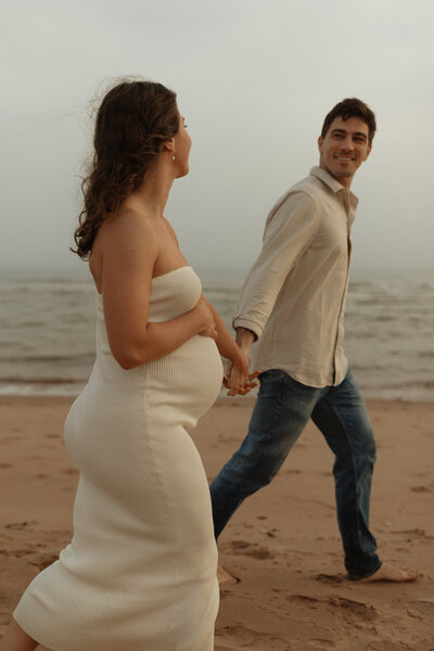 couple walking on beach for lifestyle maternity session in pei
