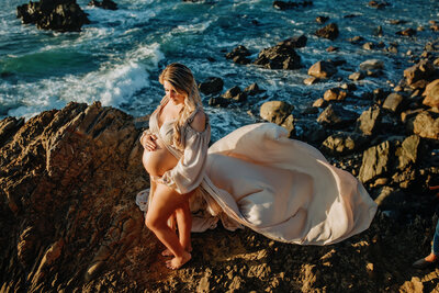 maternity portrait of mother standing on rock in big sur
