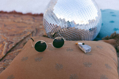 Sunglasses sitting next to a disco ball.