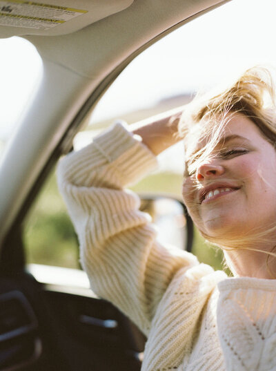 Happy woman with hair out of car window, smiling in Los Angeles