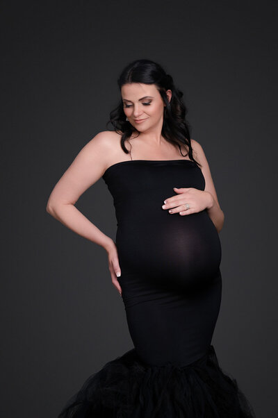 elegant lady dressed in formal black dress showing her pregnancy belly