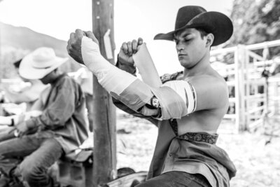 A cowboy fixing his rodeo elbow braces, a device expertly crafted and custom-made for rodeos' arms to support their riding position.