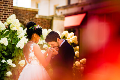 A wedding couple during the first look in front of a garden in Detroit. The groom is kissing the brides hands