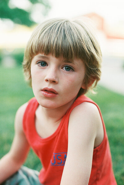 boy in red shirt sits on grass