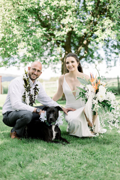 Bride and groom sitting on ground with their dog on their wedding day taken by Spokane Wedding Photograpeher