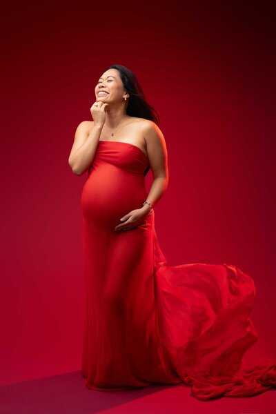 smiling pregnant woman posed with hand on belly