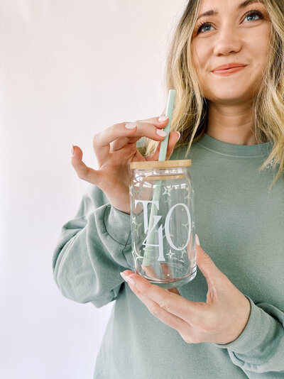 Woman holding a True40 branded cup with a straw