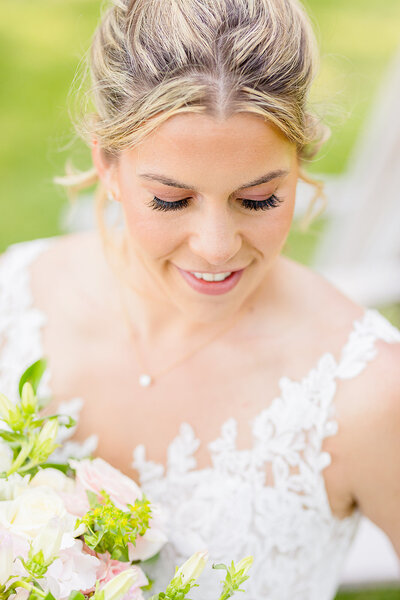 Bride looking down at her flowers to show off her incredible bridal makeup