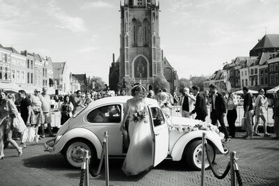 Bruid stapt uit auto voor de kerk, vastgelegd door trouwfotograaf Julia de Groot