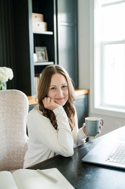 headshot of woman leaning on her hand as her elbow rests on the table in front of her captured by brand photographer