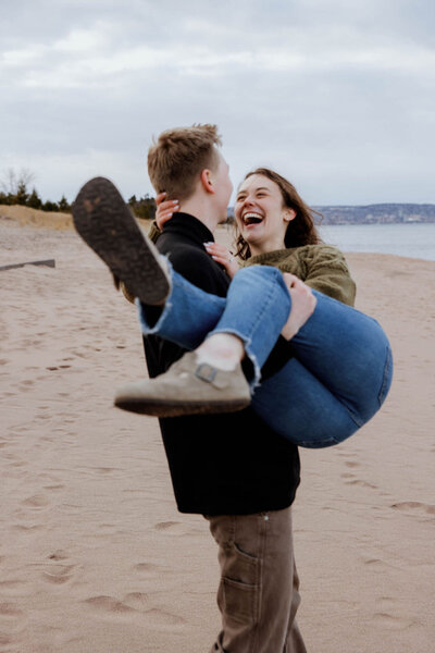 Fiance holding his future wife along the beach during their engagement session.