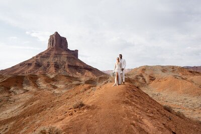 Couple holding hands in front of one of moabs most beautiful outcropped mountain.