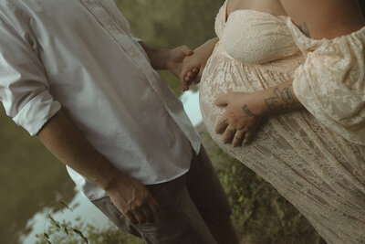 Intimate maternity photo capturing a close-up of the baby bump as the couple holds hands