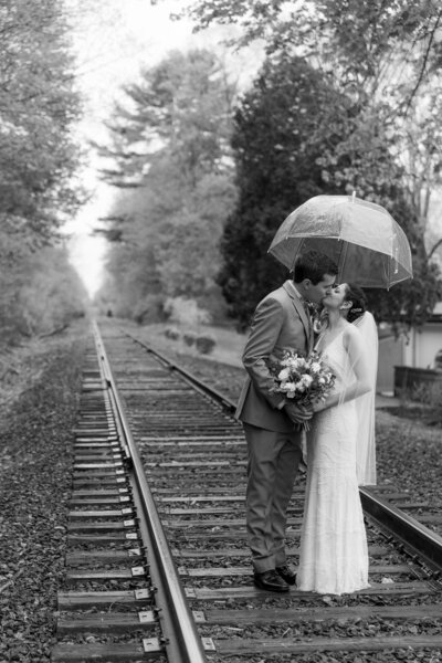 black and white bridal portrait on abandoned train tracks in the rain