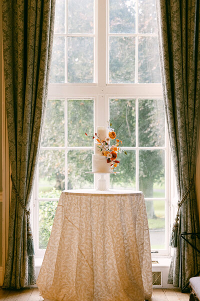 A wedding day photo of the wedding cake in front of a window at Luttrellstown Castle