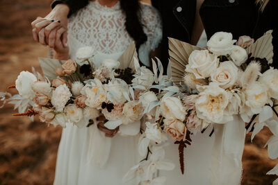 newlyweds with arms around eachother holding floral bouquets