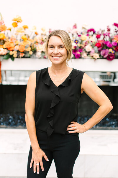 Megan Schmidt, CEO and owner of SoHo63, a Chandler wedding and event venue, smiles while posing indoors against a modern backdrop featuring neutral architectural decor. Her confident and welcoming presence reflects the leadership behind this popular Arizona event space.