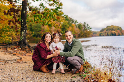 Mother and father cradle baby bump by a lake