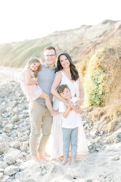 Family photographer, Kristin Wood, smiles for family portrait with her husband and two children