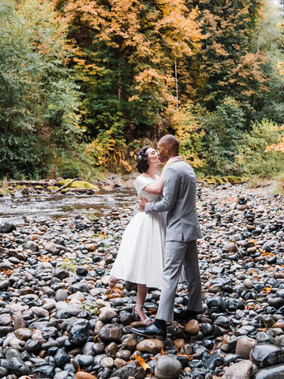 A bride and groom kiss near the river after their Pacific Northwest elopement at Treehouse Point