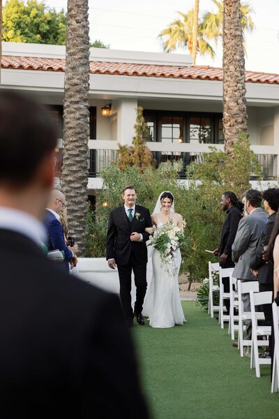 wedding party walks in the desert with parasols