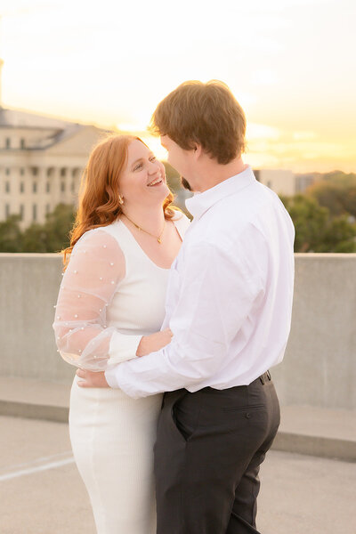 man and woman standing by lake laughing and hugging